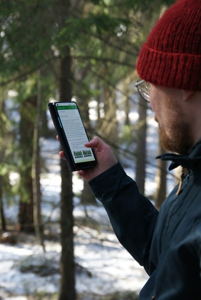 Henkilö selaa maastotaulukot-sovellusta puhelimelta