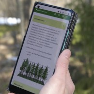 maastotaulukot sovellus puhelimessa henkilön kädessä metsässä